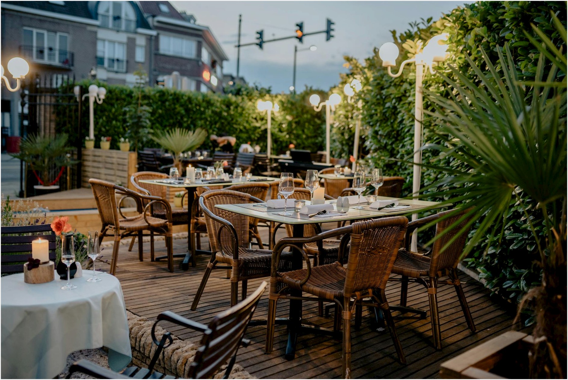 Charming restaurant terrace with wicker chairs and glowing lights, perfect for a relaxed evening.