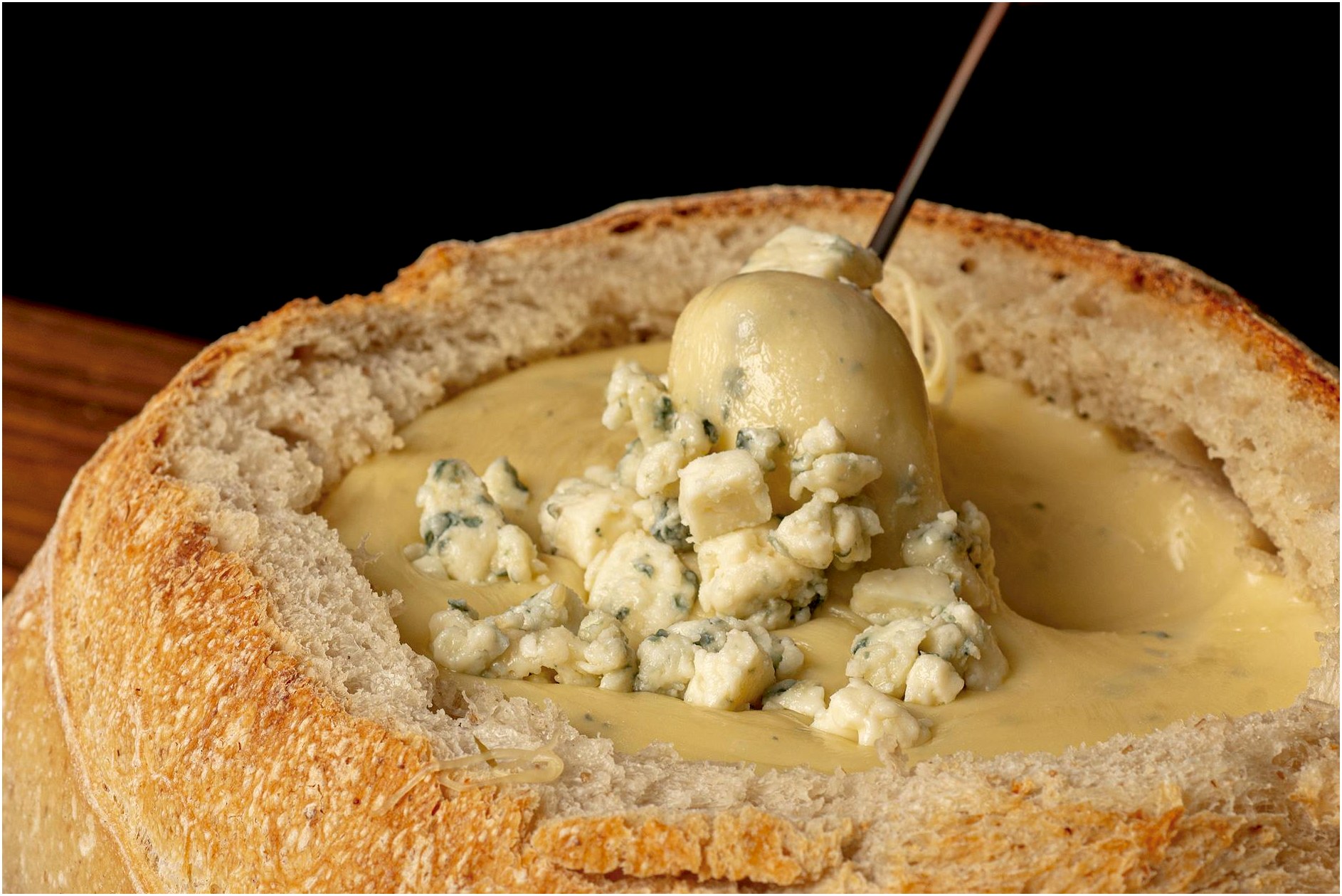 Close-up of creamy blue cheese fondue in a homemade bread bowl. Perfect comfort food.