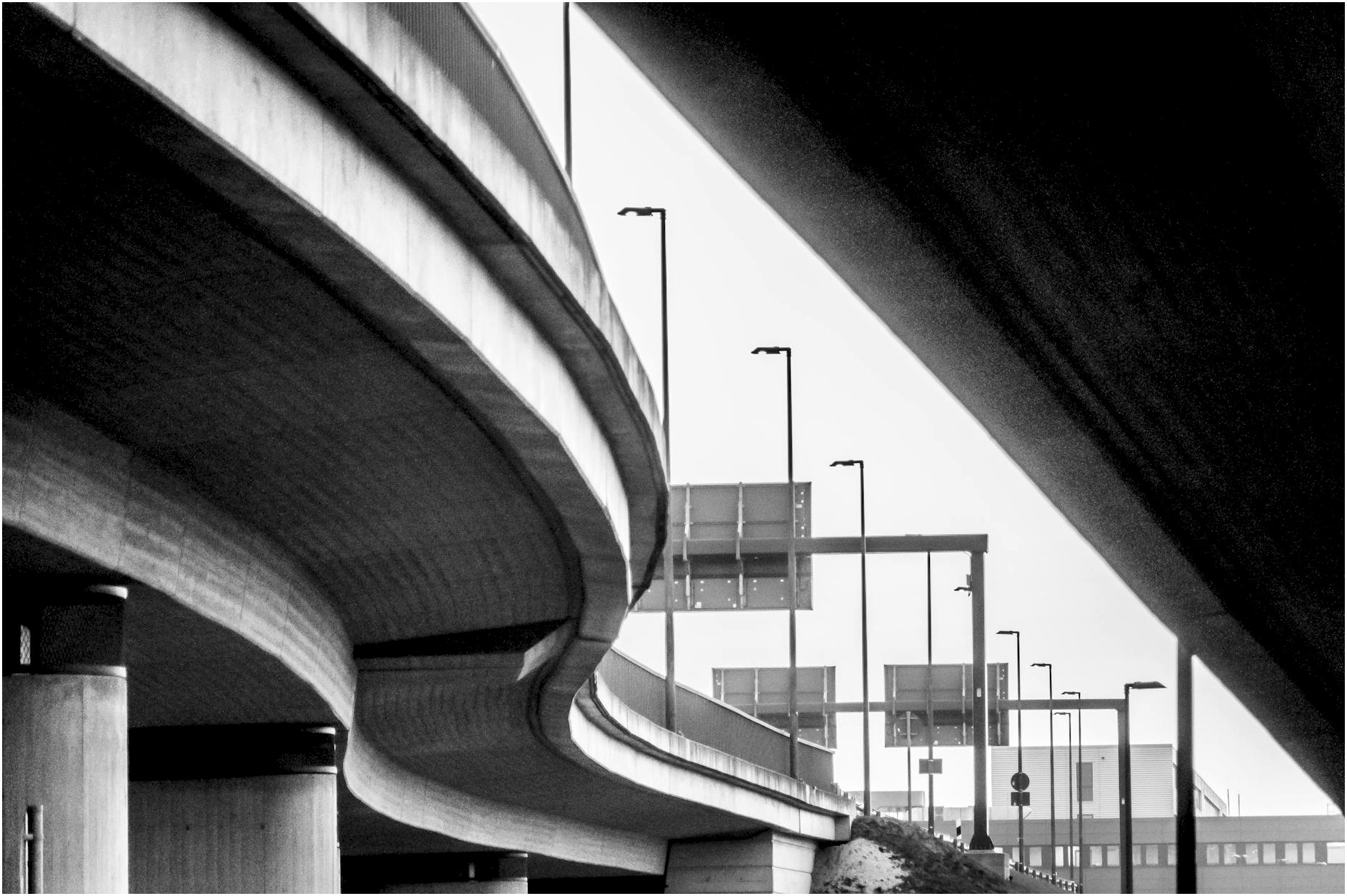 Dramatic black and white capture of urban highway interchange with dynamic curves and lines.