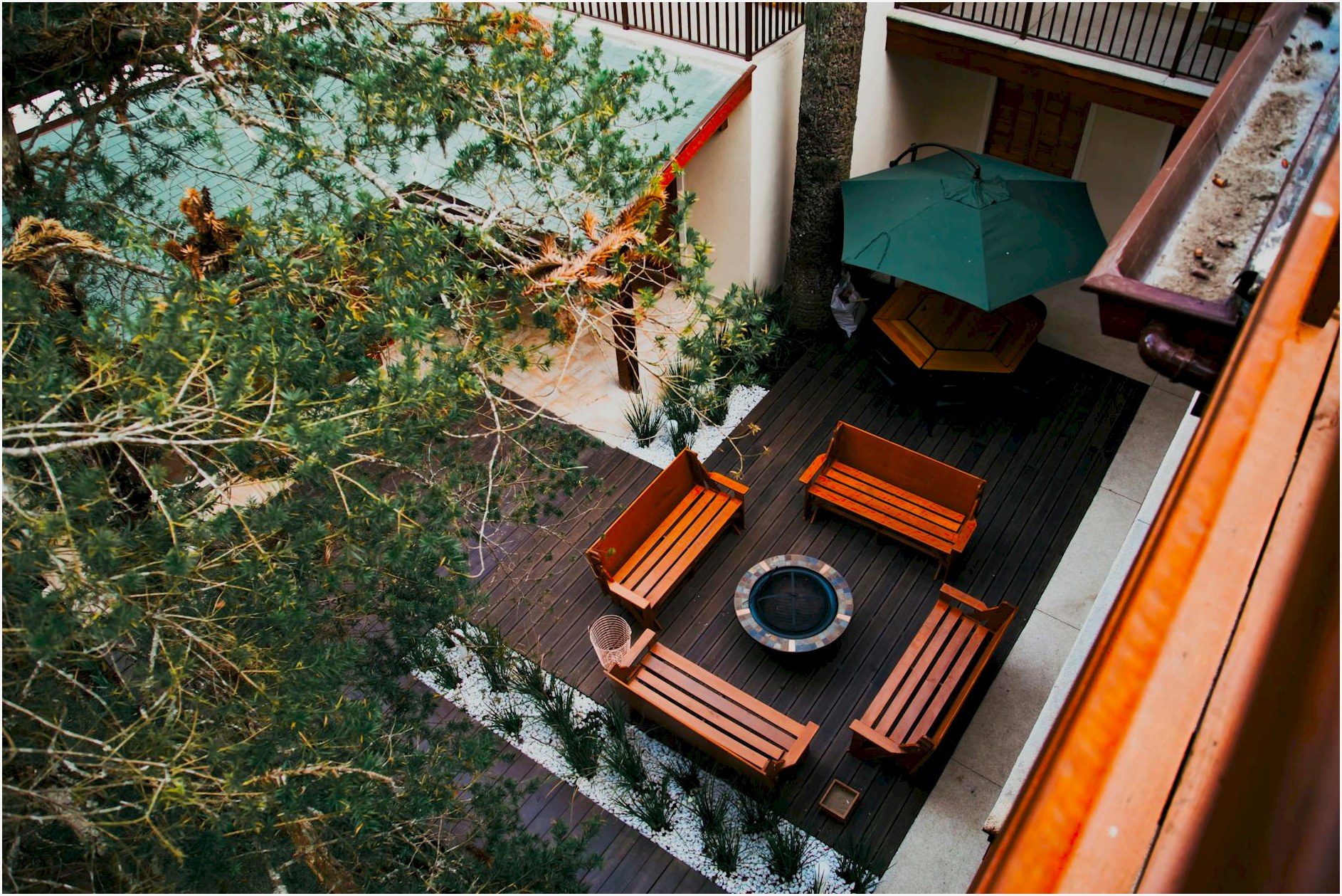 Top-down view of a serene outdoor courtyard with wooden seating and greenery.